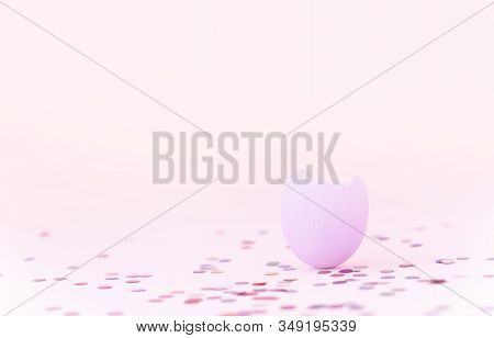Purple Easter Eggshell On Pastel Pink Background With Colorful Confetti. Egg Is A Symbol Of The Cele