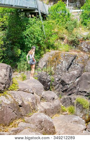 Young Woman Standing On High Rock Deciding Where To Go Next  Around Dramatic And Rugged Mclaren Fall