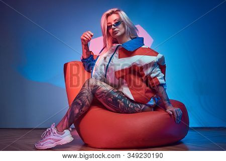 Avantgarde Portrait Of Young Woman With Tattoo On Her Leg, She Is Sitting On Bean Bag.