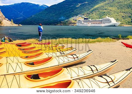 Kayaks On Shore And Cruise Ship On Fjord In Norwegian Tourist Destination Flam Village.