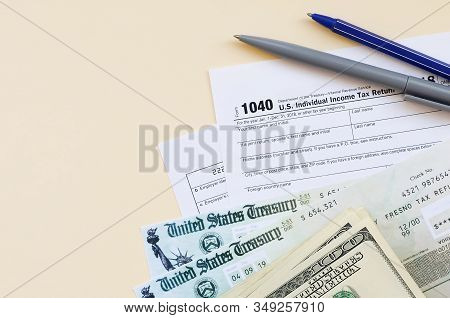 1040 Individual Income Tax Return Form With Refund Check And Hundred Dollar Bills On Beige Backgroun