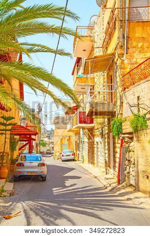 Netanya, Israel - May 19, 2009:  Old typical strret in Netanya with palm and parked cars on sunny summer day