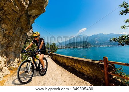 Cycling woman and man riding on bikes in mountains at Garda lake landscape. Couple cycling MTB enduro flow sentiero ponale trail track. Outdoor sport activity.