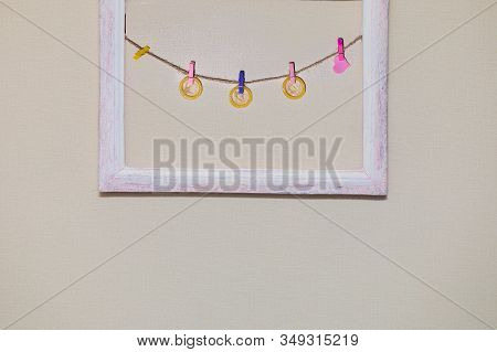Condoms And A Heart On Clothespins Hanging On A Rope In A Frame