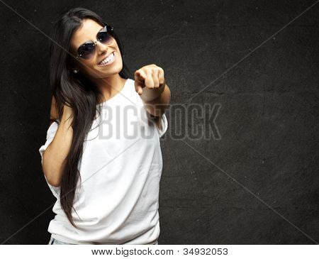 Portret van een jonge vrouw die hart sungalasses wijzen tegen een muur grunge