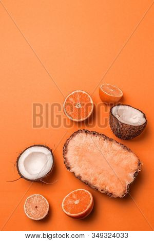 Top View Of Assorted Exotic Fruits On An Orange Background. Pineapple, Coconut, Orange And Lemon Hal