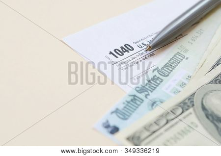1040 Individual Income Tax Return Form With Refund Check And Hundred Dollar Bills On Beige Backgroun