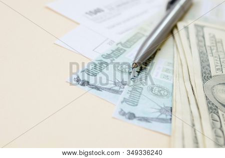 1040 Individual Income Tax Return Form With Refund Check And Hundred Dollar Bills On Beige Backgroun