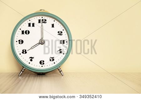 Antique Analog Clock With Hands Set At 08:00. 20:00 The Alarm Clock Is On The Table