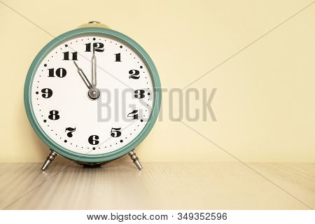 Antique Analog Clock With Hands Set At 11:00. 23:00 The Alarm Clock Is On The Table