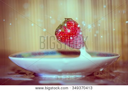 A Strawberry Dropped Into A Saucer Of Milk Bouncing Back Up With Milk Spilled And Droplets Splatteri
