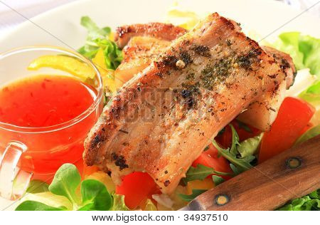 น้ำกับหมูสามชั้นที่ทอดบนผักกาดหอมมะเขือเทศสดและมะนาว