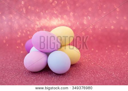 Multi-colored Purple, Pink, Blue, Yellow Easter Eggs On A Pink Shiny Bokeh Background. Symbol Of Cel