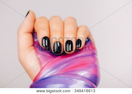 Hands With Black Manicure Holding Slime In Blue And Pink Vibrant Colors