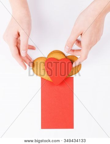 Female Hands Put Heart Shape Cookies With Red Greenting Card On A White Backround. Simbol Of Cozy Lo