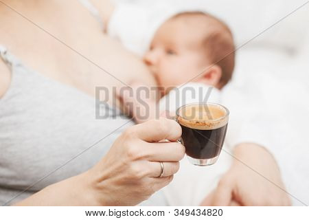 Mother breastfeeding newborn baby while drinking coffee. Breastfeeding and caffeine consumption concept
