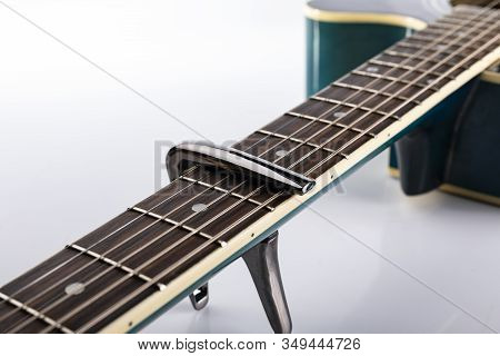 A Capotasto On A Fretboard Of Acoustic Guitar, On A White Background, Close-up.