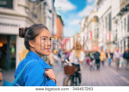 Tourist chinese young woman walking in city street shopping on travel vacation in fall autumn spring happy. Copenhagen city, Denmark.