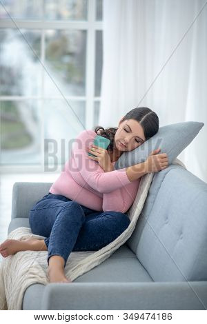Full-figured Young Woman In A Pink Shirt Sitting On A Sofa With A Smartphone