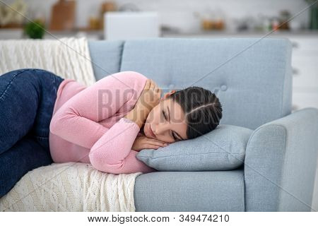 Full-figured Young Woman In A Pink Shirt Lying On A Sofa And Thinking