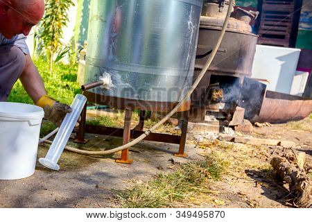 Man Takes A Sample Of Freshly Distillated Liquor, Alcohol In The Laboratory Graduated Cylinder.