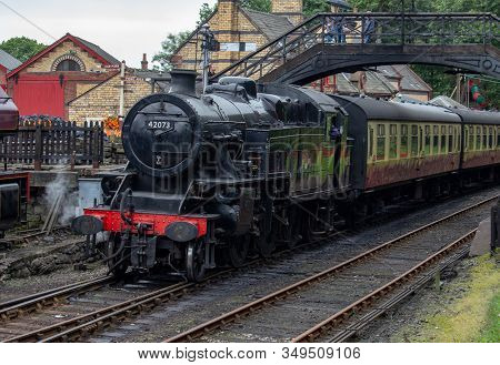 An Old Steam Trains Comes So A Slow Halt Beneath A Bridge