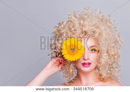 Beautiful Fashionable Blonde Girl With Voluminous Curly Hairstyle, Bare Shoulders And A Sunflower In