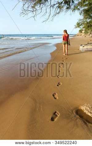Woman Walking Along The Beach Looking At The Waves