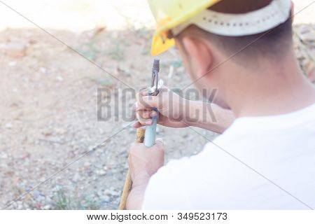Worker Fixing Water Pipe Spinger In The Garden.