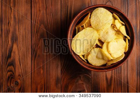 Wavy, Potato Chips In A Plate On A Wooden Table. Top View Snacks. Stock Photo Potato Chips With Empt