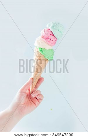 Stack Of Pastel Colorful Ice Cream Scoops In Waffle Cone, Isolated On Light Blue Background. Woman H