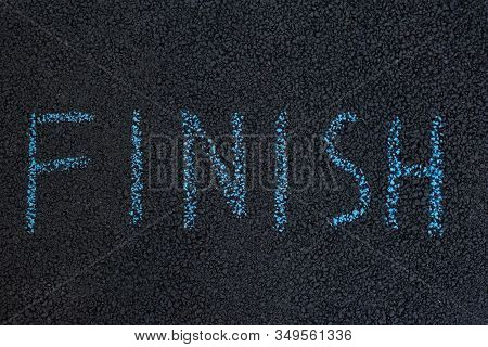 Text Finish Underfoot. Black Asphalt With Chalk Inscription. The End Concept.