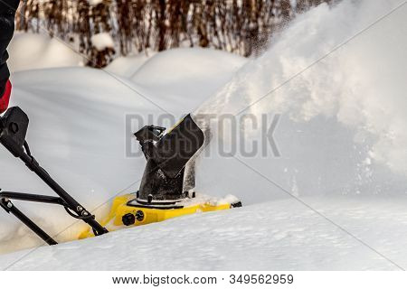Man Is Brushing White Snow With The Yellow Electric Snow Thrower In A Winter Garden