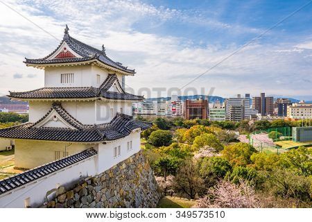 Akashi, Hyogo, Japan castle tower and downtown cityscape with cherry blossoms in spring.