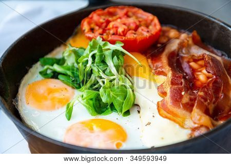 Grilled toasts served with beans, scrumbled eggs and sausage for an English breakfast