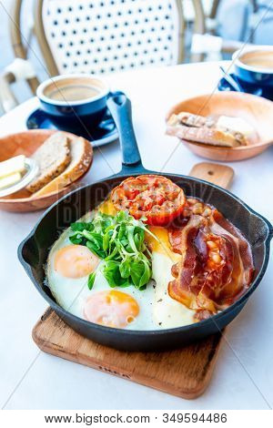 Grilled toasts served with beans, scrumbled eggs and sausage for an English breakfast