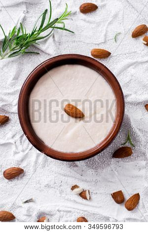 high angle view of an earthenware bowl with menjar blanc, a dessert made with almonds and sugar typical of Catalonia, Spain, on a white textured surface