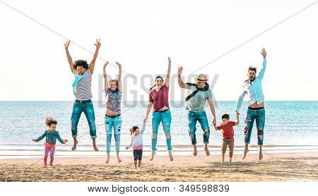 Happy Multiracial Families Jumping Together At Beach Holding Hands - Summer Vacation Concept With Yo