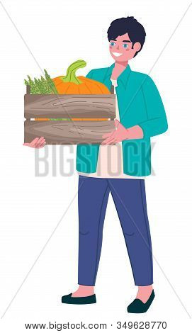 A Handsome Young Farmer With Blue Eyes And Black Hair Is Holding A Wooden Box With Pumpkin And Aspar