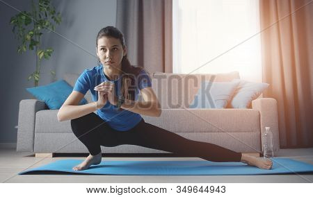 Young Concentrated Woman Doing Side Lunge Yoga Position Training On Roll Mat On Floor At Home