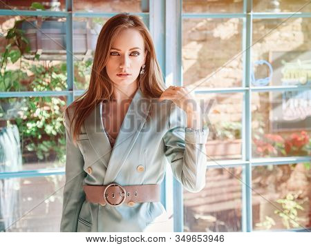 Professional Model With Long Blond Hair In A Mint Jacket Against The Background Of Loft Windows Posi