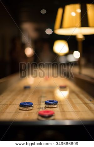 Playing The Game Of Shuflleboard In A Dark Bar