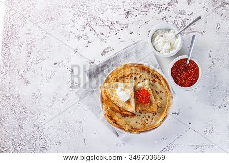 Traditional Russian Crepes Blini Stacked In A Plate With Red Caviar, Fresh Sour Cream On Light Backg