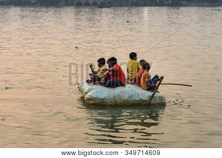 Kolkata, India - March 11, 2019: Indian Children Sail On Homemade Raft On Hooghly Or Ganga In Sunset