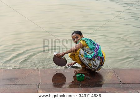 Kolkata, India - March 11, 2019: Indian Woman Washes Dishes In River Hooghly Or Ganga At Mallick Gha