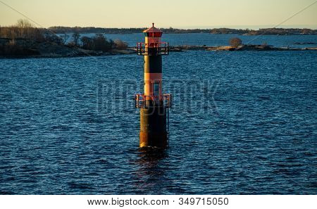 Lighthouse In The Strait Between The Islands Of The Stockholm Archipelago, Lit By The Rays Of The Su