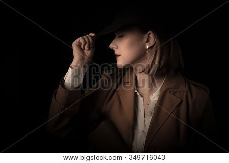 Retro Gangster Woman In A Brown Cloak And Black Hat With Airguns In Hands. Style Of The Mafia. Blurr