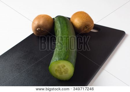 A Cucumber And Two Kiwis Lie On A Black Cutting Board. Diet Food And Salads For A Healthy Lifestyle.