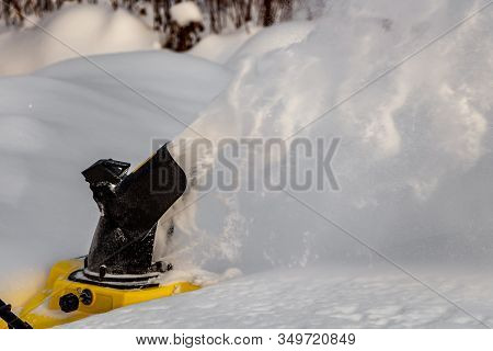 Man Is Brushing White Snow With The Yellow Electric Snow Thrower In A Winter Garden