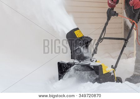 Man Is Brushing White Snow With The Yellow Electric Snow Thrower In A Winter Garden